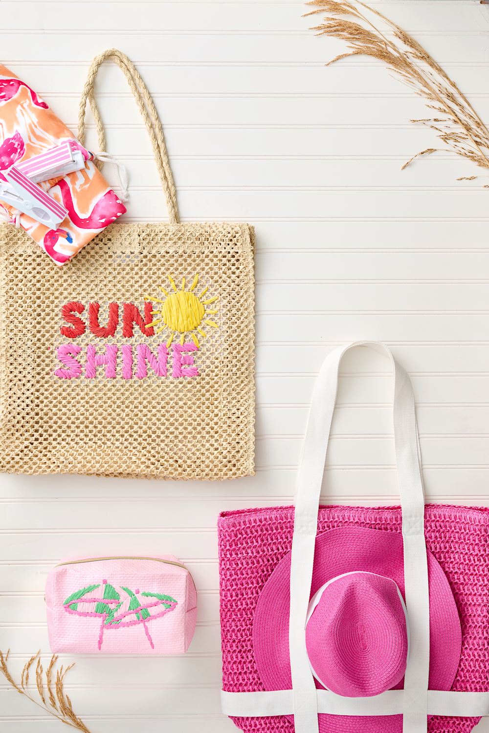 Woven bag with 'Sunshine' text, pink pouch, and yoga mat on a light wooden surface.
