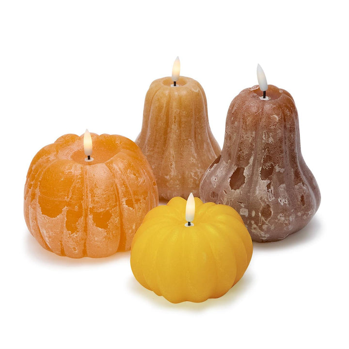Four decorative candles shaped like pumpkins on a white background