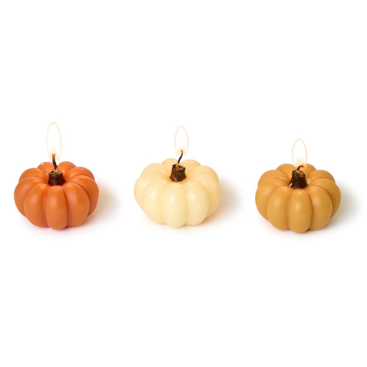 Three pumpkin-shaped candles on a white background