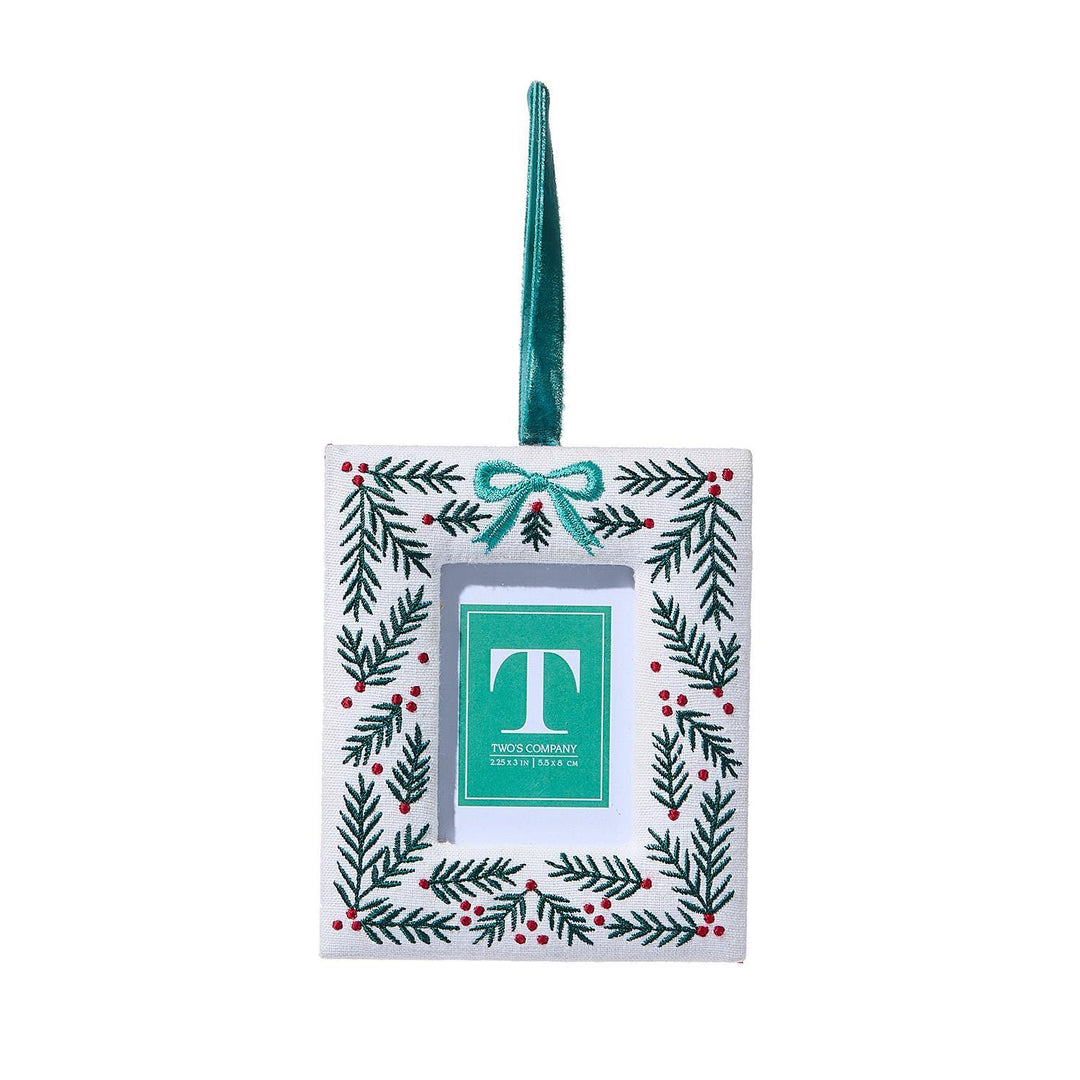 Decorative Christmas ornament with green bow and leaf pattern on a white background