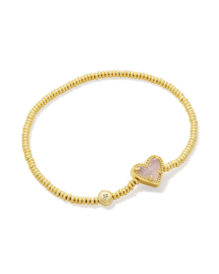 Gold bracelet with a heart-shaped charm on a white background