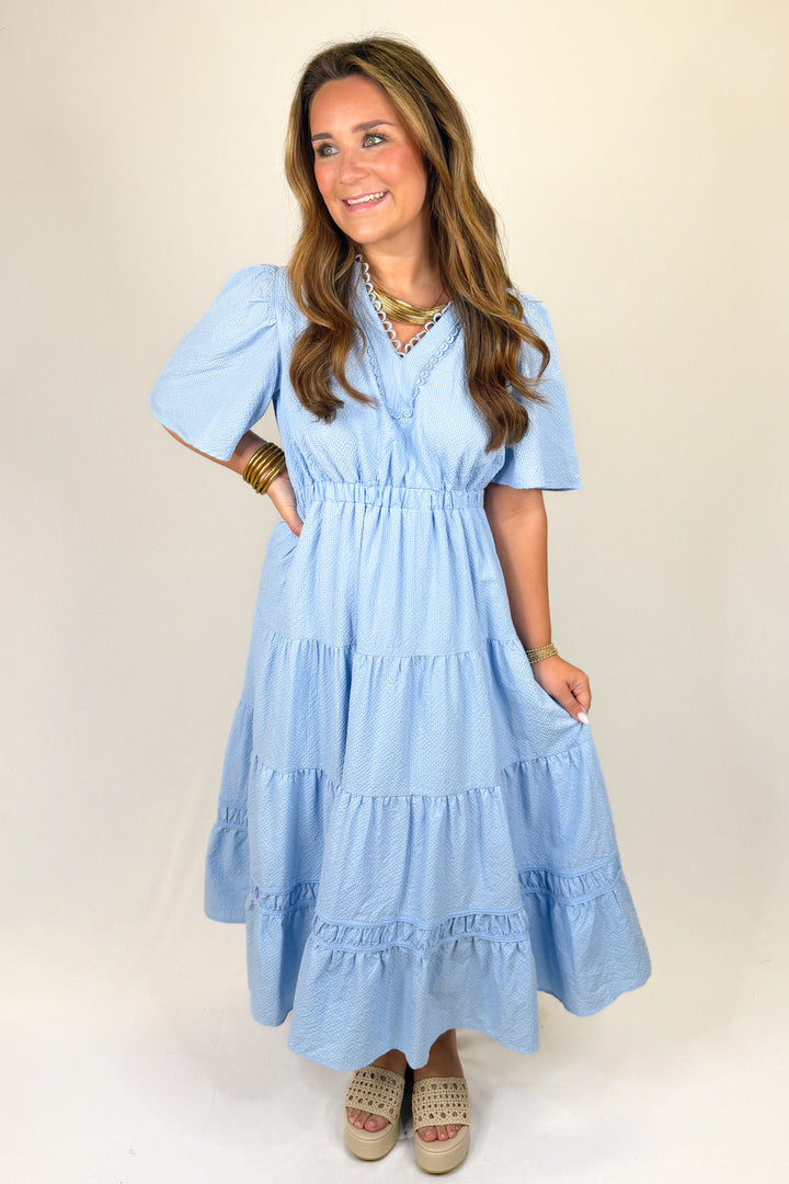 Woman wearing a light blue dress with a plain background