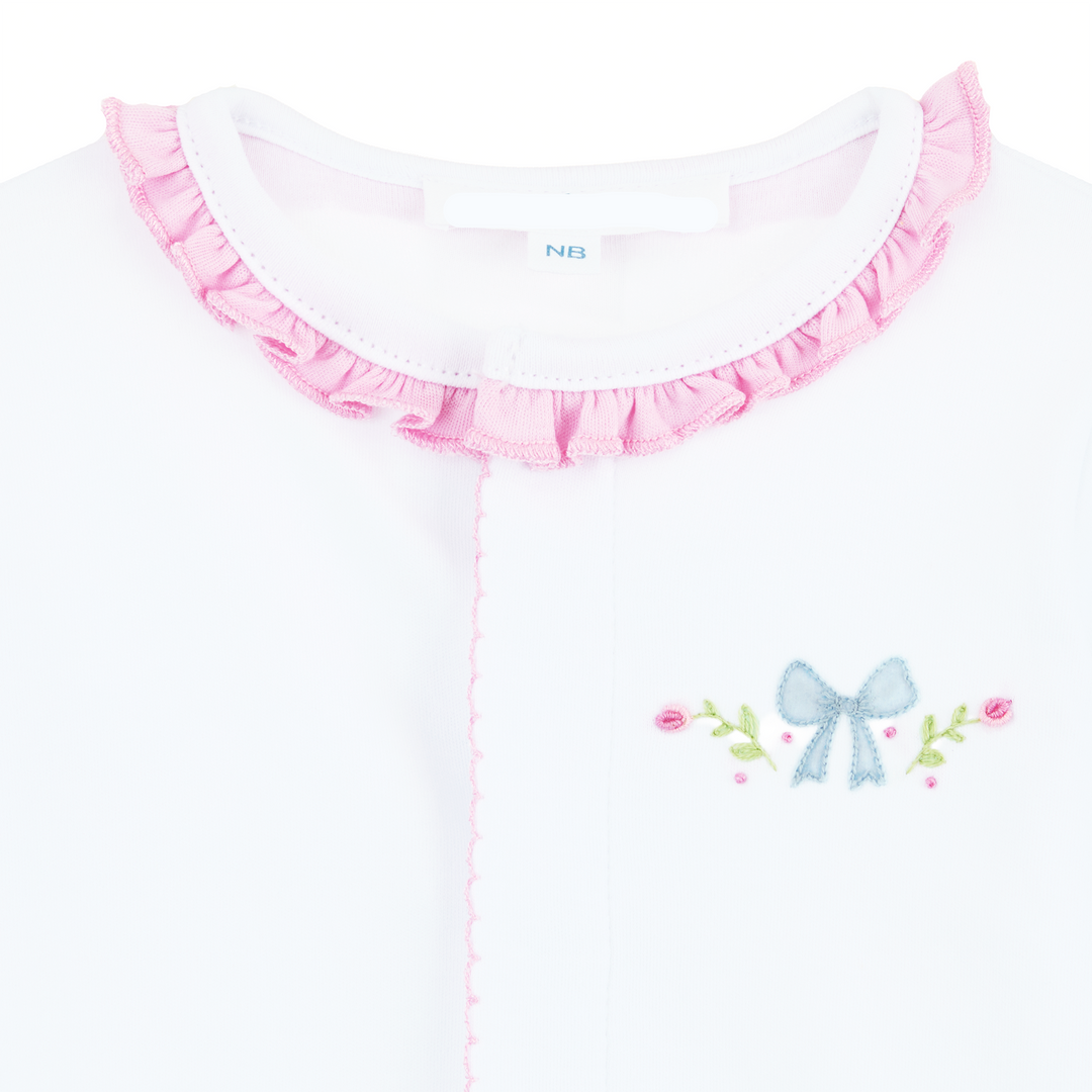 CLOSE UP SHOT OF WHITE CONVERTER GOWN WITH PINK RUFFLE TRIM DETAIL AND BOW WITH FLORAL EMBROIDERY 