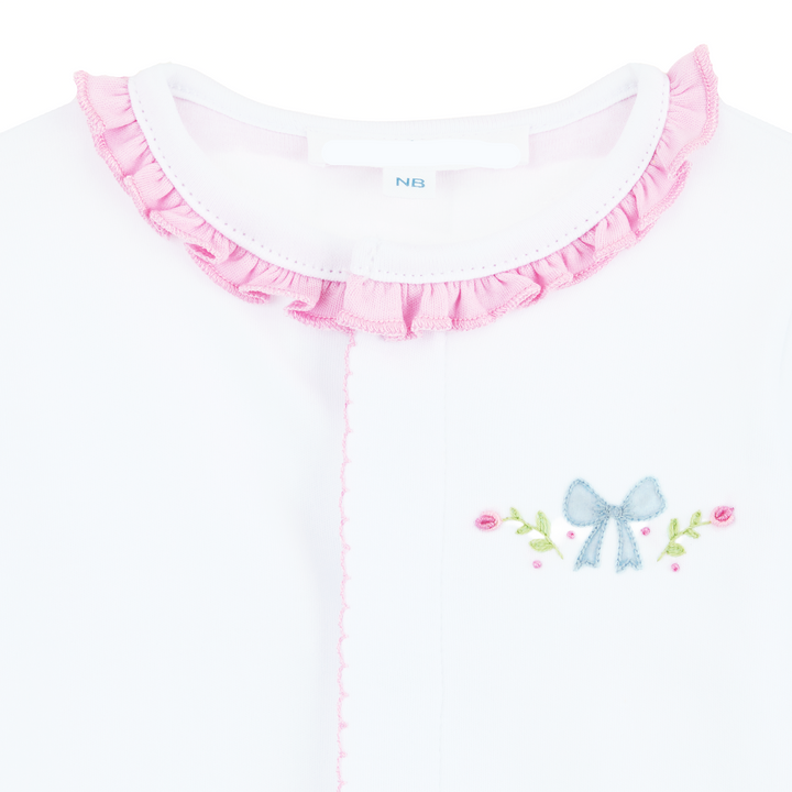 CLOSE UP SHOT OF WHITE CONVERTER GOWN WITH PINK RUFFLE TRIM DETAIL AND BOW WITH FLORAL EMBROIDERY 