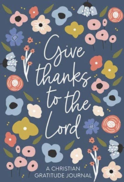 Front cover of a Christian gratitude journal with the phrase 'Give thanks to the Lord' in large white script, surrounded by colorful illustrated flowers on a dark blue background.