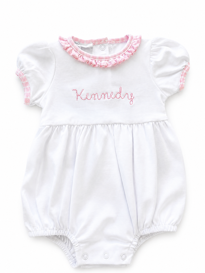 White baby romper with pink ruffled collar and embroidered name on a white background