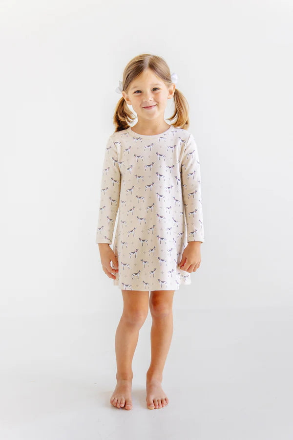 Young girl wearing a long-sleeve dress with a pattern on a white background