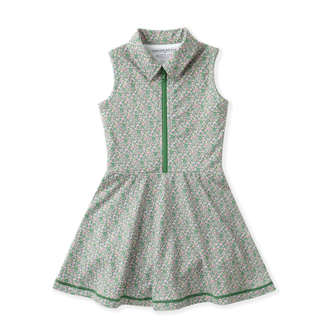 A sleeveless children's dress with a small green and pink floral print on a white background, featuring a green half-zip collar, green trim, and a flared skirt.