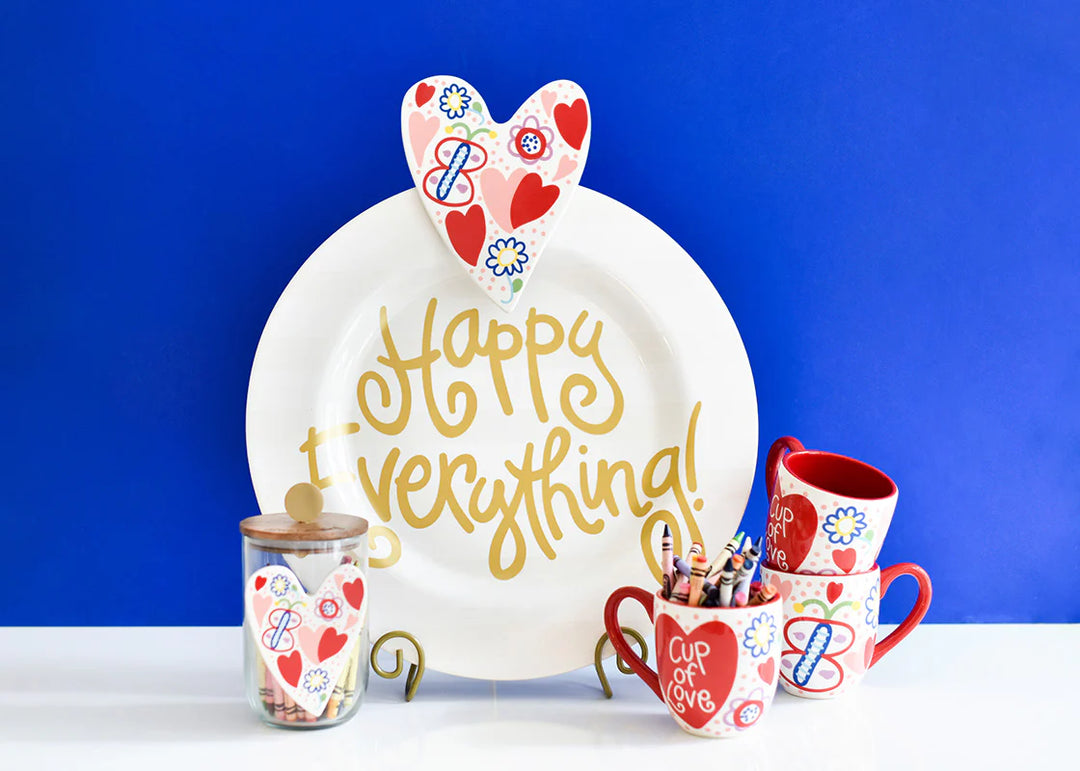 Decorative items including a plate, mugs, and shot glass with heart designs on a blue background.