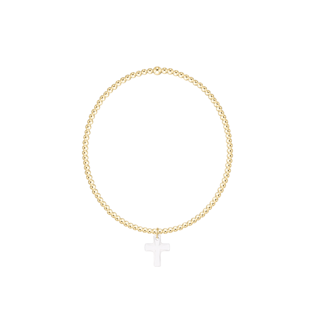 Gold bracelet with a white cross pendant on a white background