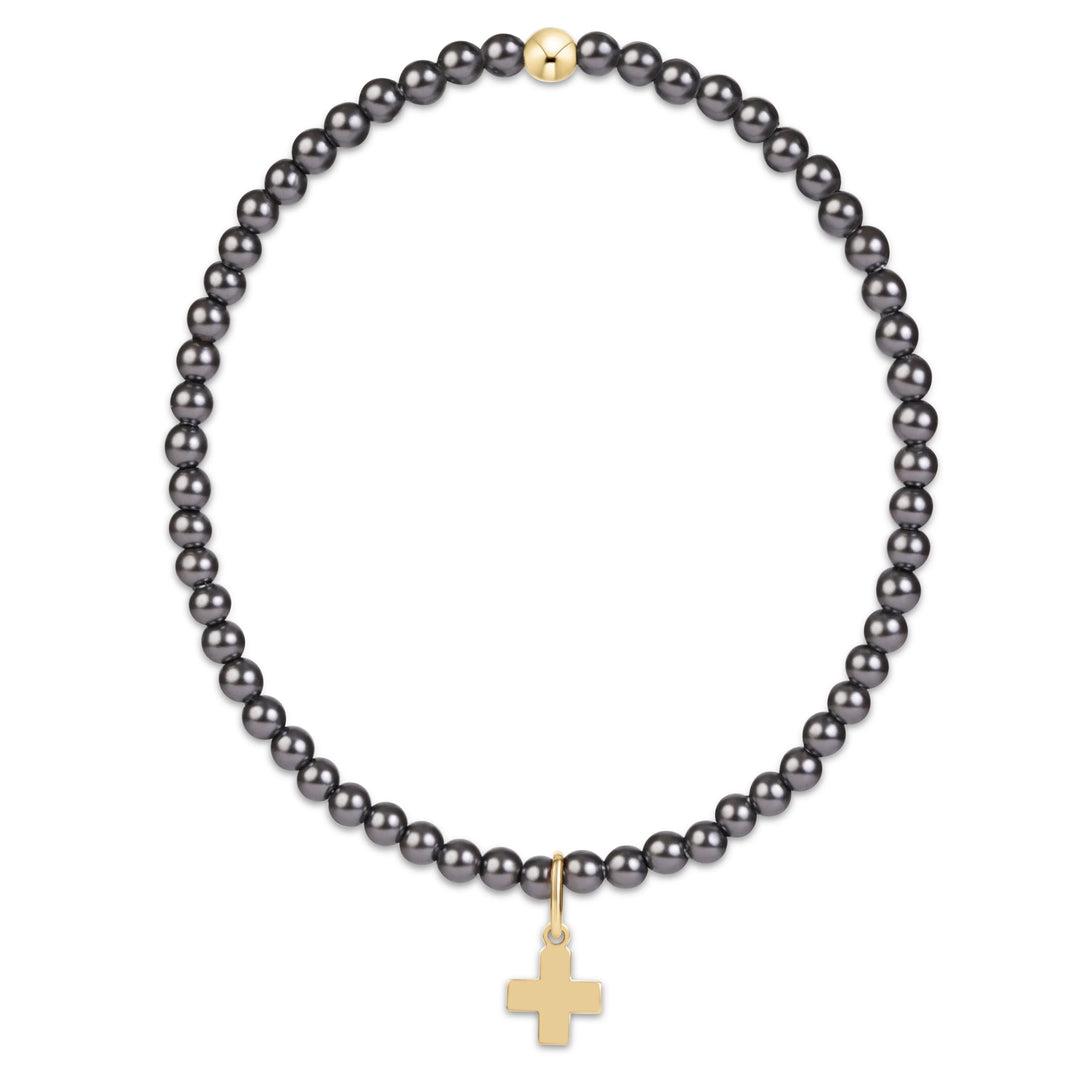 gray beaded bracelet with small gold cross charm on white background
