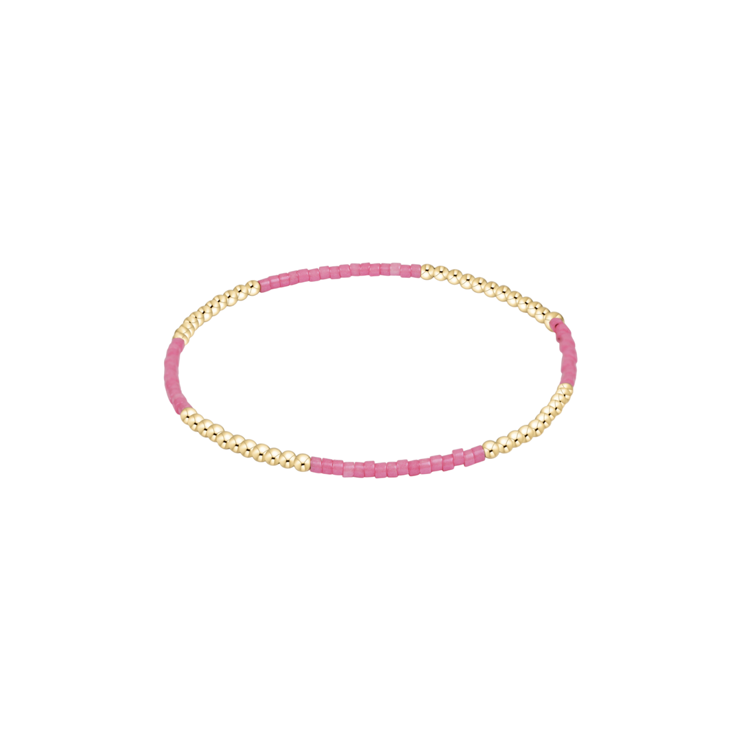 Bracelet with pink beads and gold accents on a white background