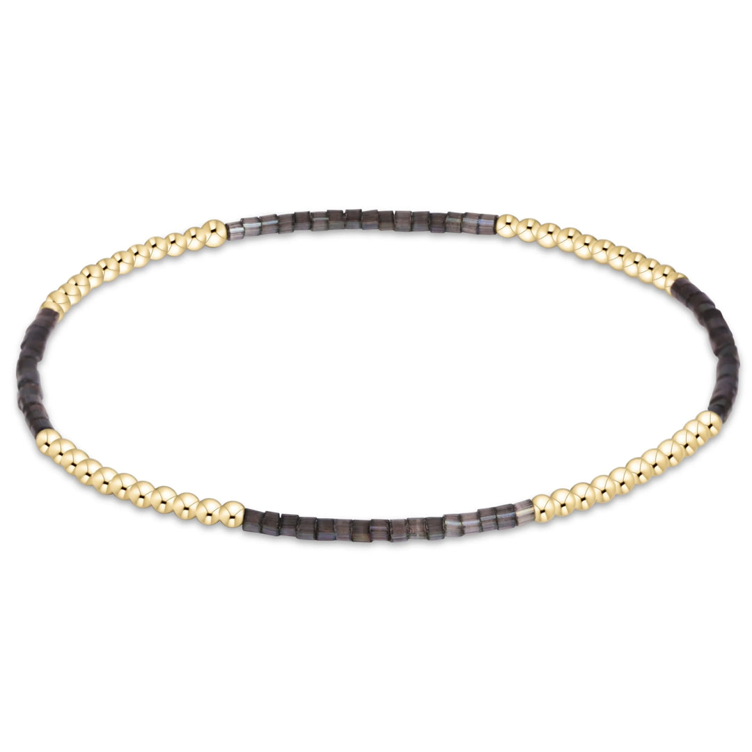 BLACK AND GOLD BEADED BRACELET ON WHITE BACKGROUND