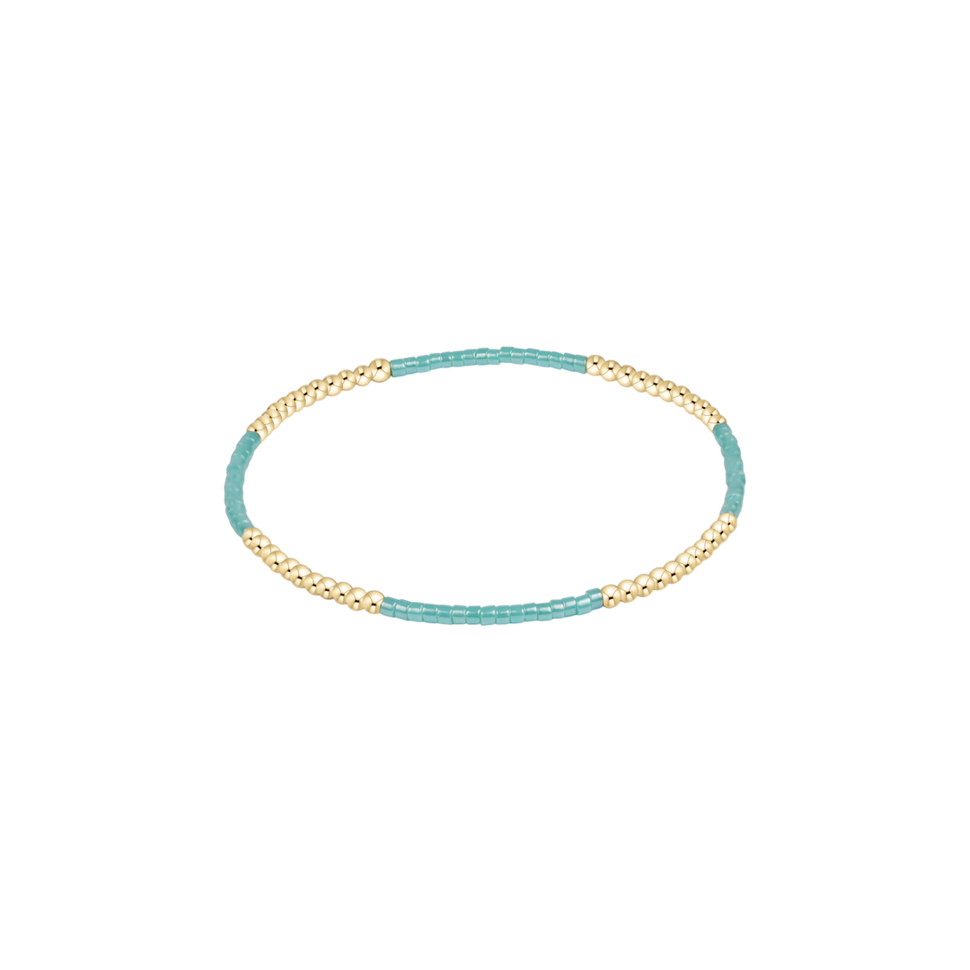 Turquoise and gold beaded bracelet on a white background