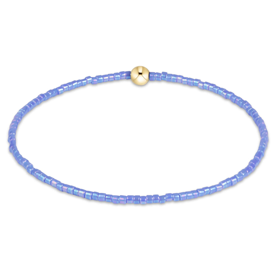 LIGHT BLUE BEADED BRACELET WITH SINGLE GOLD BEAD ON WHITE BACKGROUND