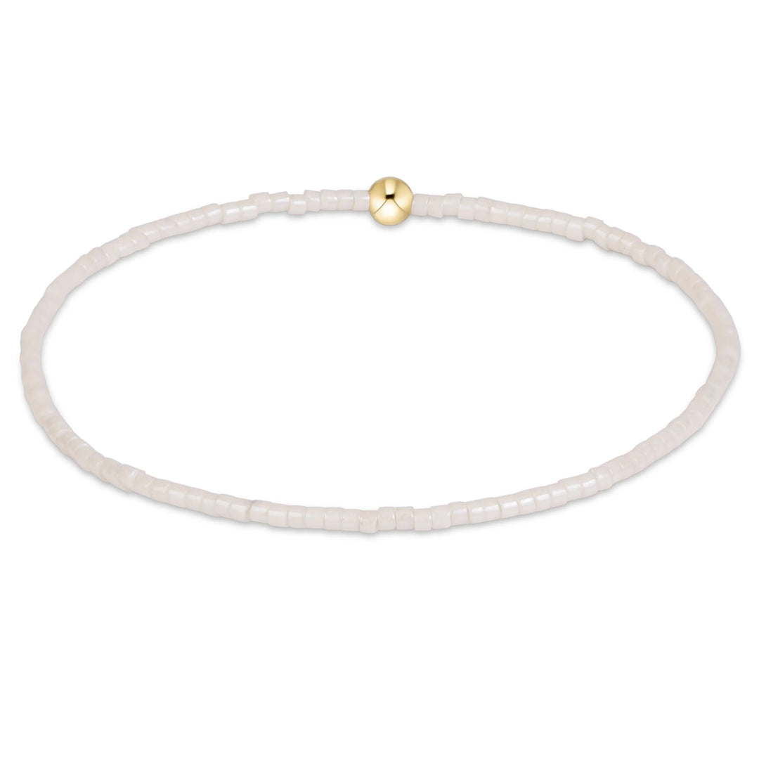 cream beaded bracelet with single gold bead on white background