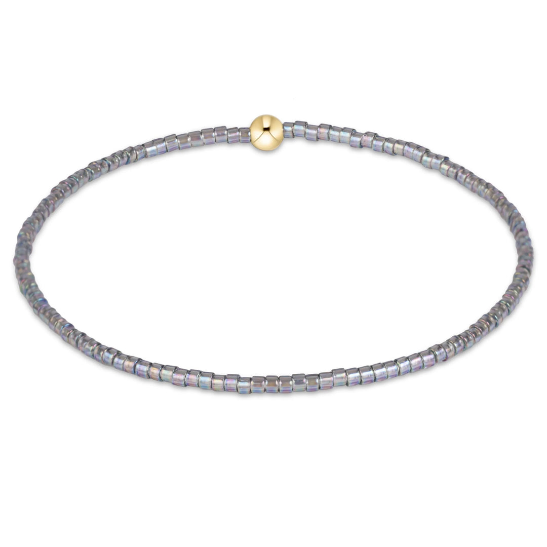 GRAY BEADED BRACELET WITH SINGLE GOLD BEAD ON WHITE BACKGROUND