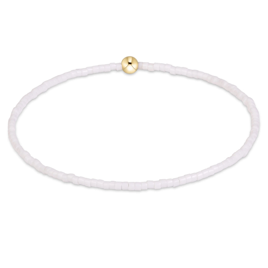 White beaded bracelet with a gold bead on a white background