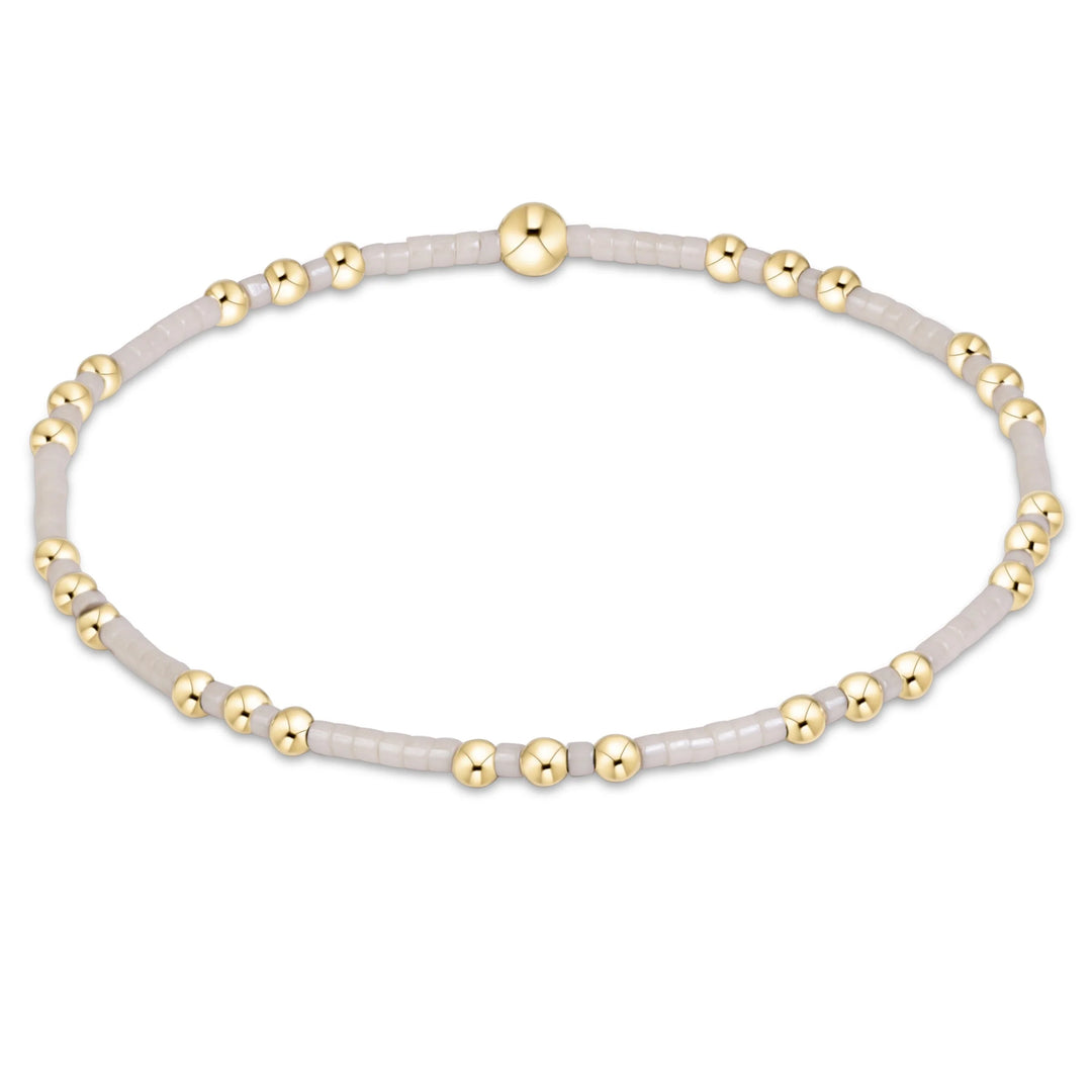 cream and gold beaded bracelet with gold beads in clusters of three
