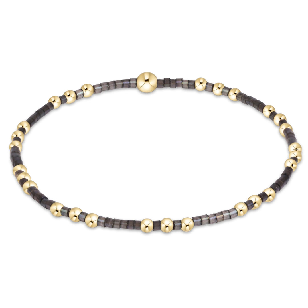gray and gold beaded bracelet on white background
