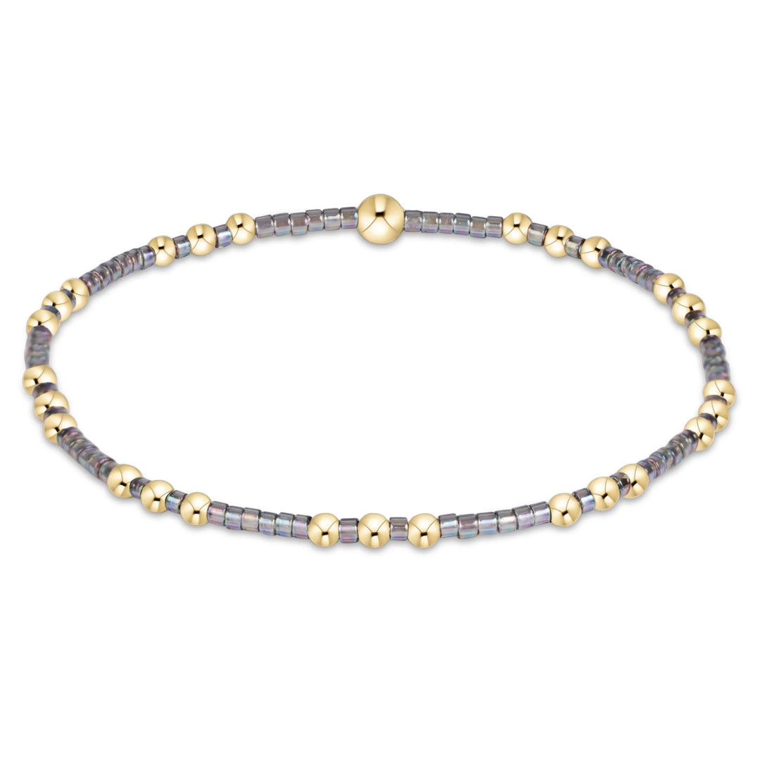 gray and gold beaded bracelet on white background