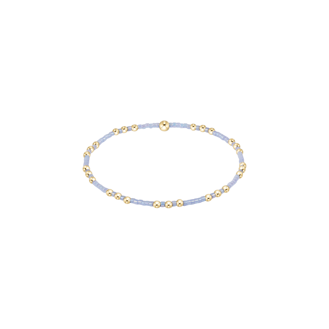 Delicate bracelet with gold and light blue beads on a white background