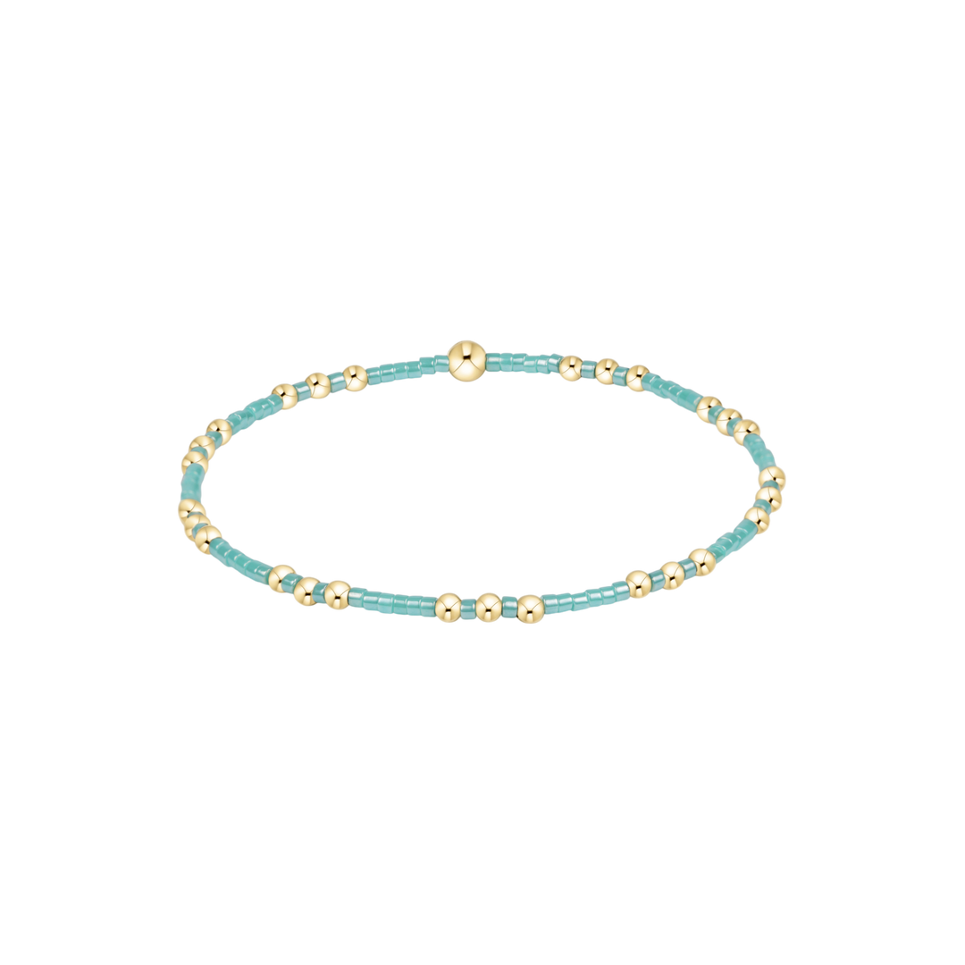 Turquoise beaded bracelet with gold accents on a white background