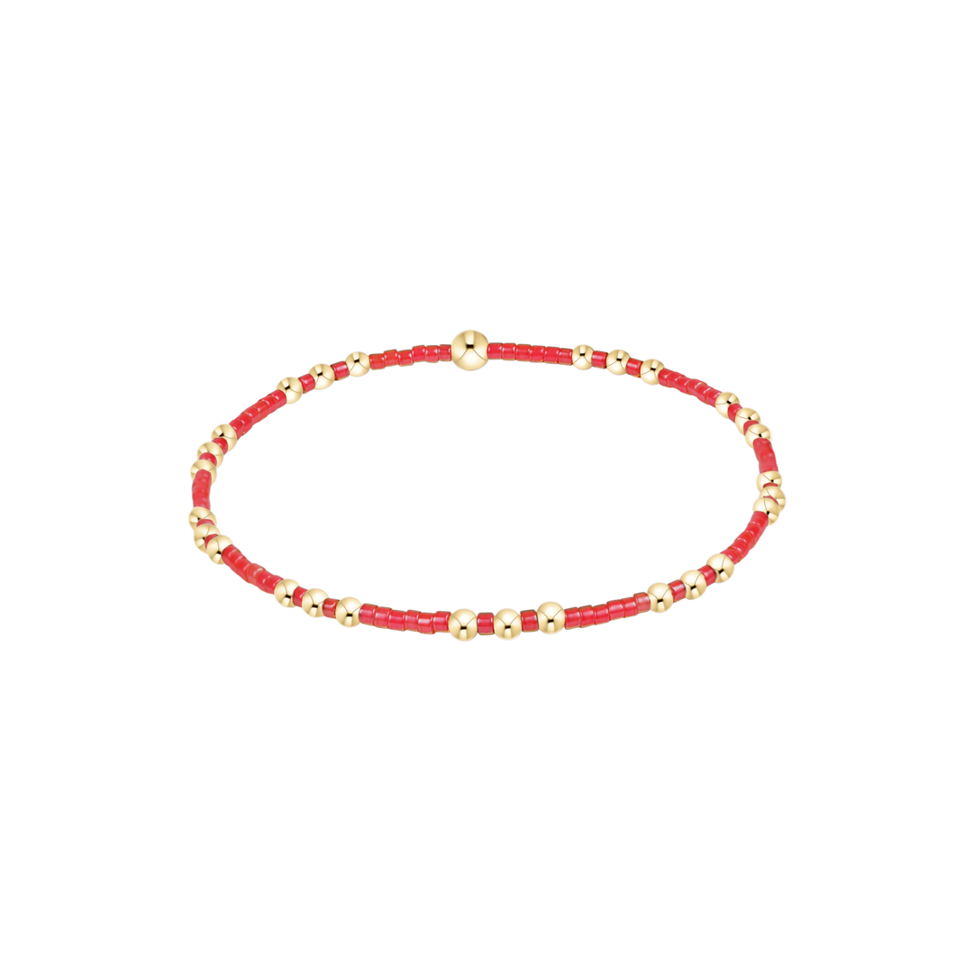 Red beaded bracelet with gold accents on a white background