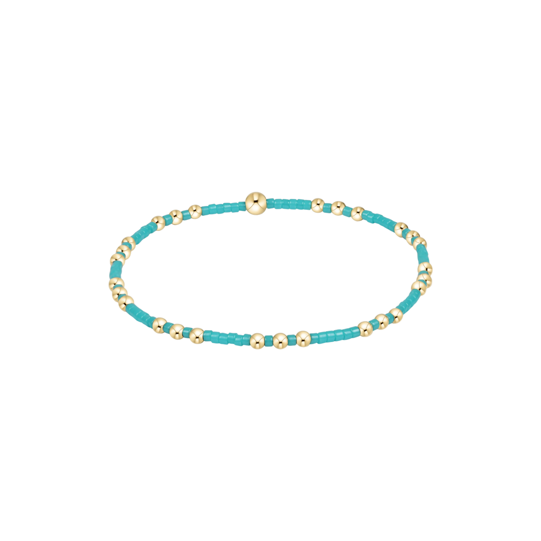 Turquoise beaded bracelet with gold accents on a white background