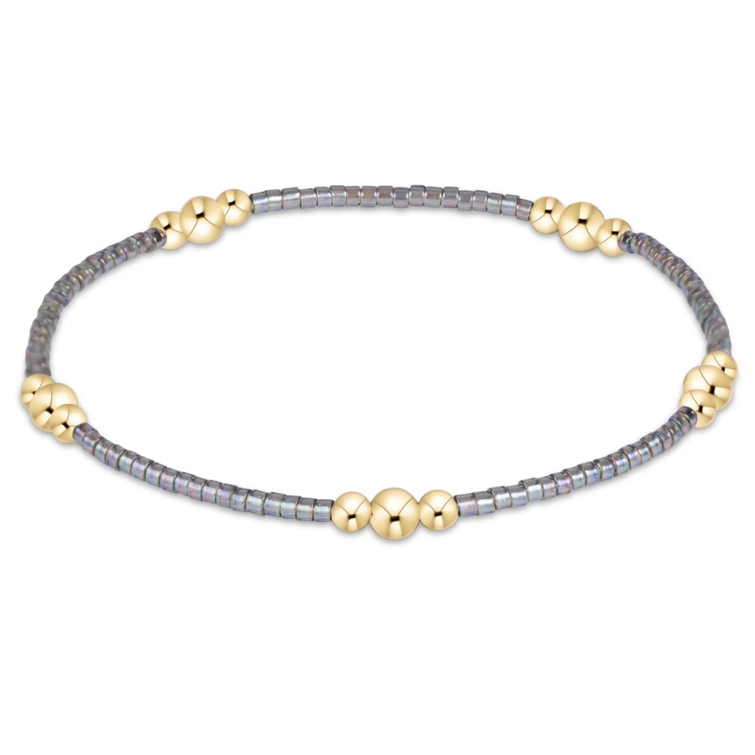GRAY BEADED BRACELET WITH 3 GOLD BEADED CLUSTERS ON WHITE BACKGROUND