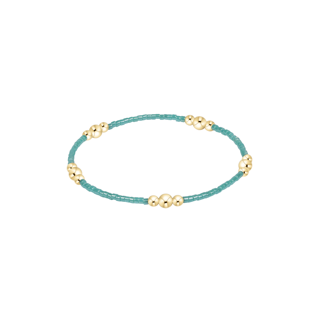 Turquoise beaded bracelet with gold beads on a white background