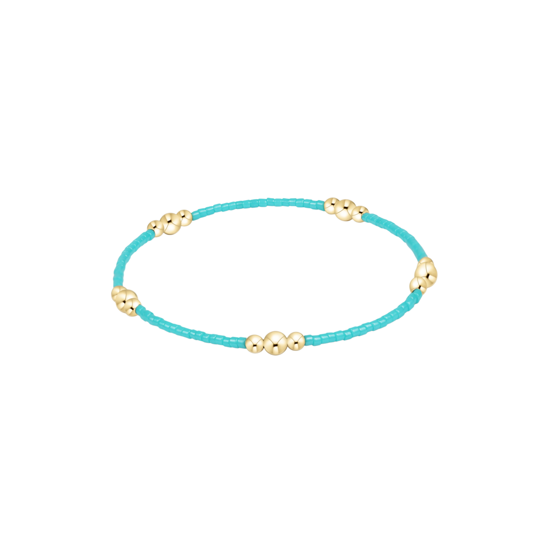 Turquoise bracelet with gold beads on a white background