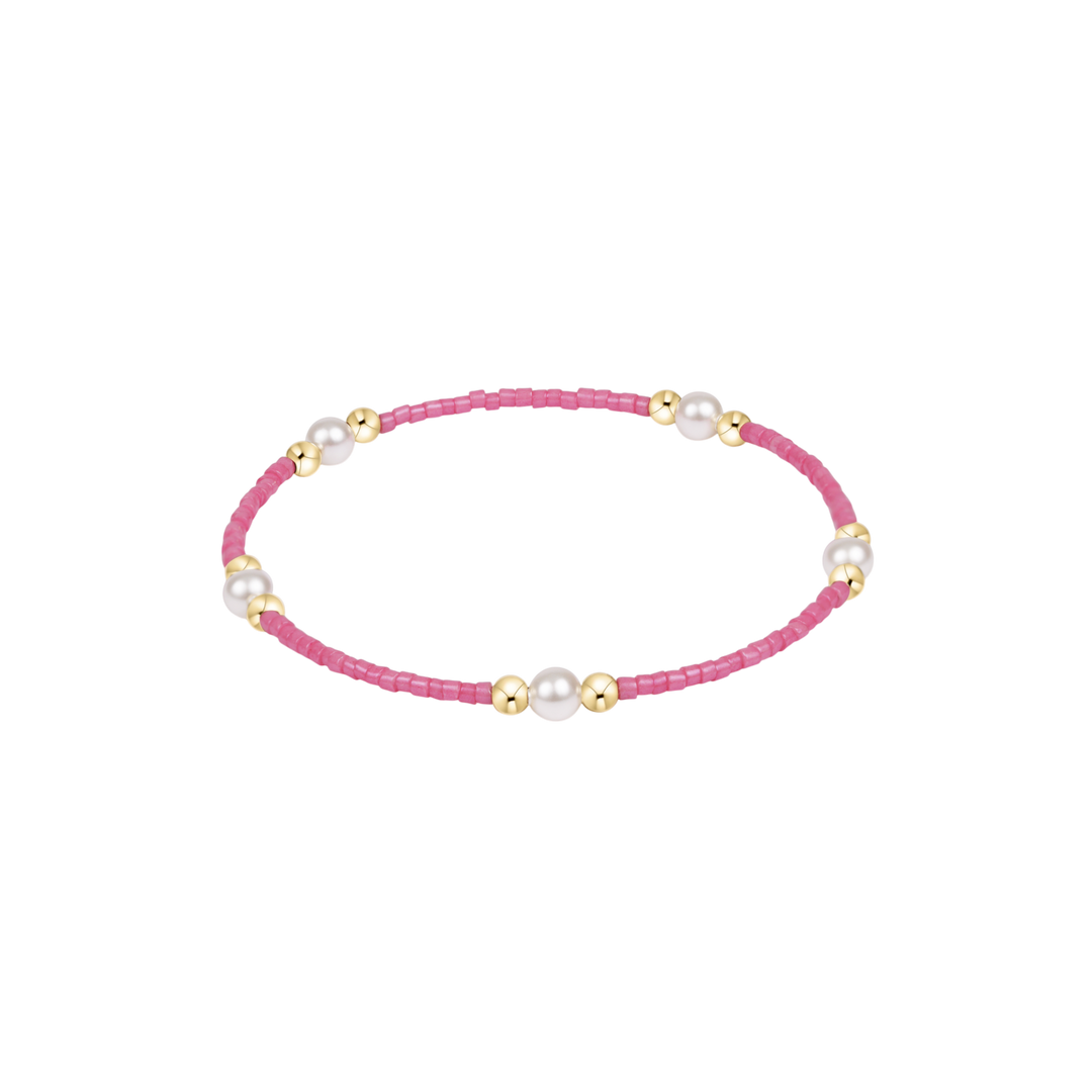 Bracelet with pink beads and gold accents on a white background