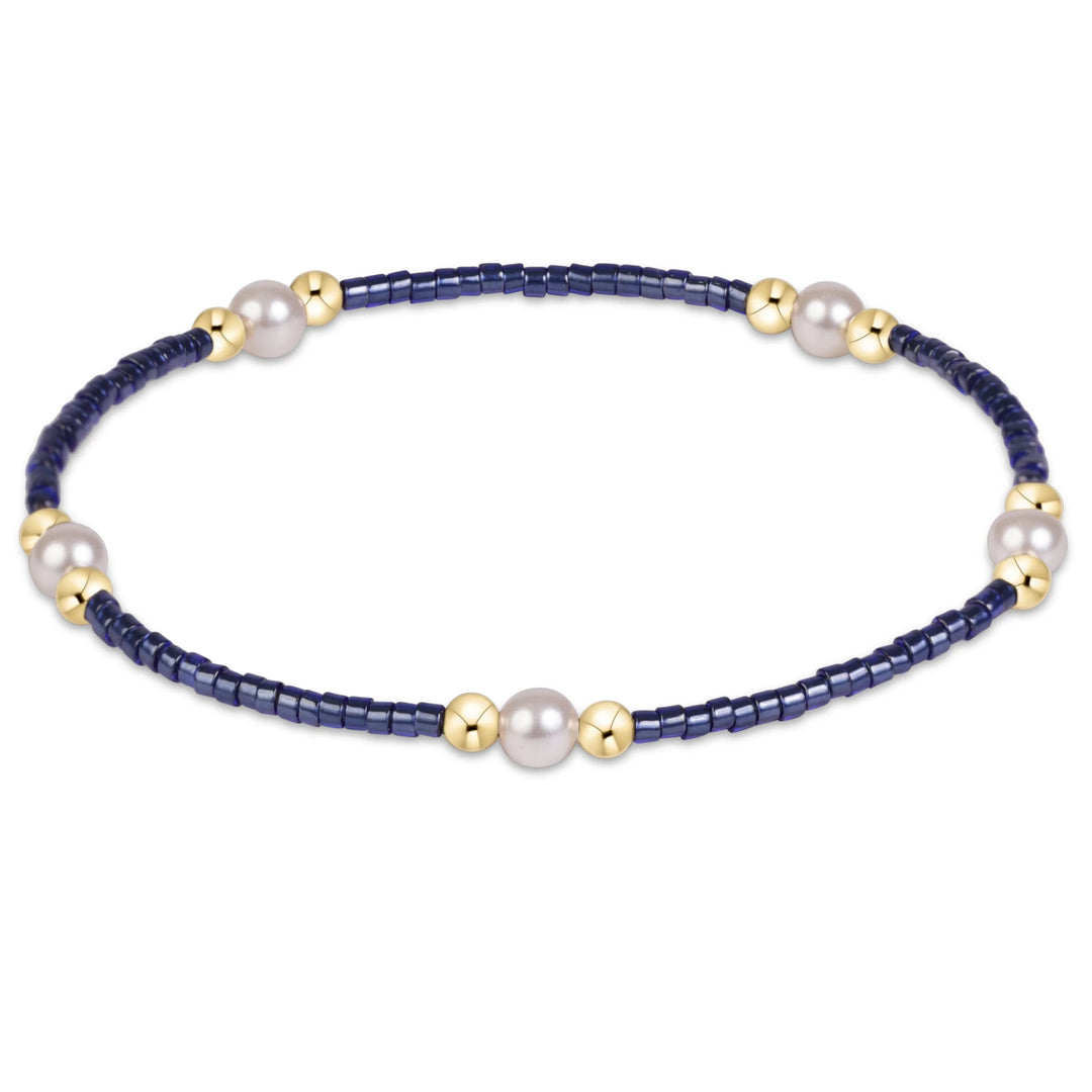 NAVY BEADED BRACELET WITH PEARL ADN GOLD CLUSTERS ON WHITE BACKGROUND