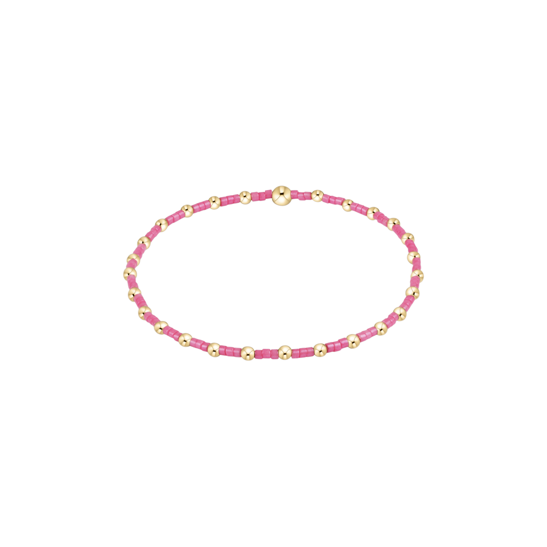 Pink beaded bracelet with gold accents on a white background