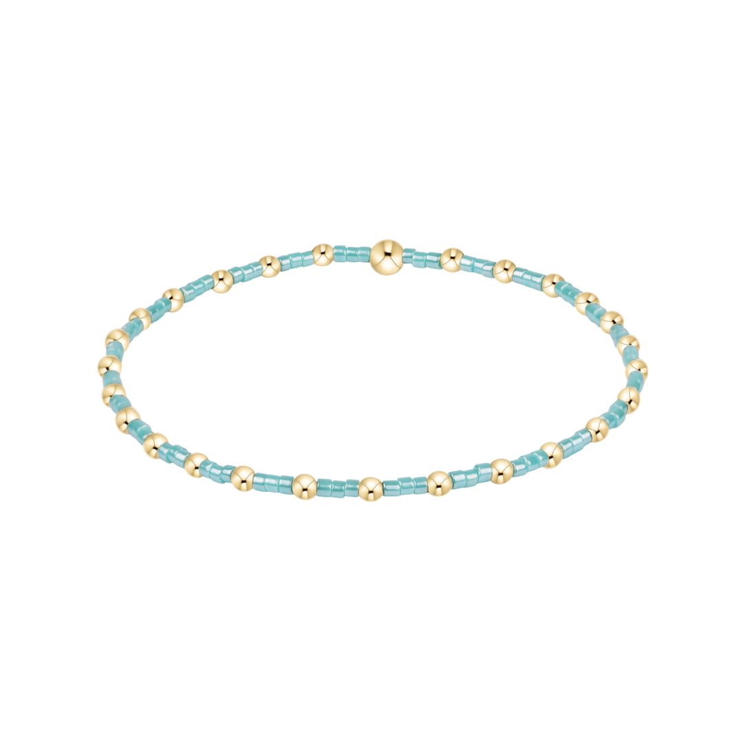 Beaded bracelet with turquoise beads and gold accents on a white background