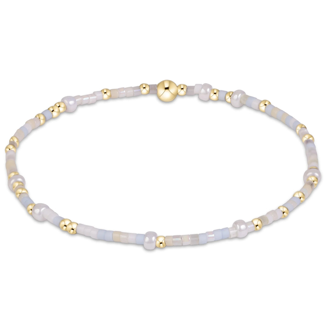 CREAM AND WHITE AND GOLD BEADED BRACELET ON WHITE BACKGROUND