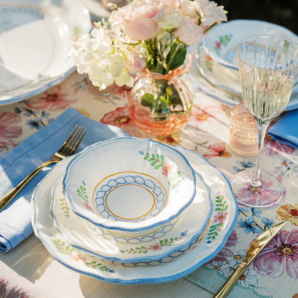 Elegant table setting with floral tablecloth, plates, bowls, and glasses.
