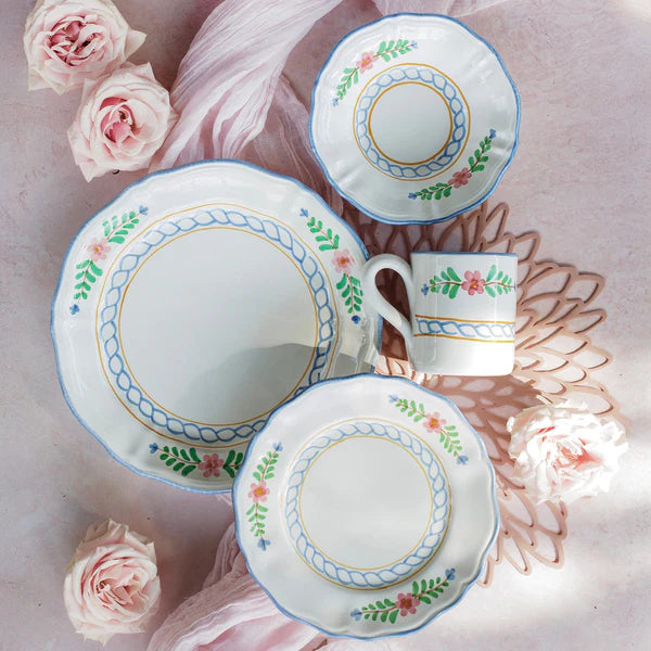 Ceramic tea set with floral patterns on a pink surface with flowers.