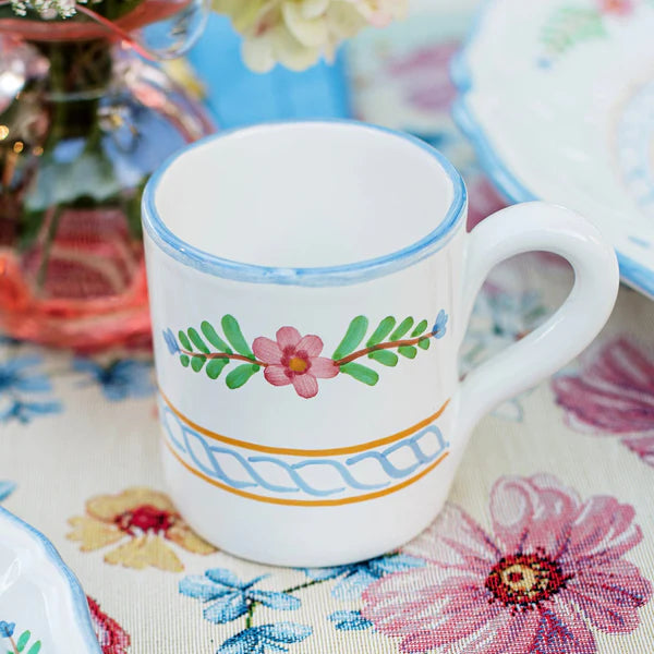 White mug with floral design on a colorful tablecloth
