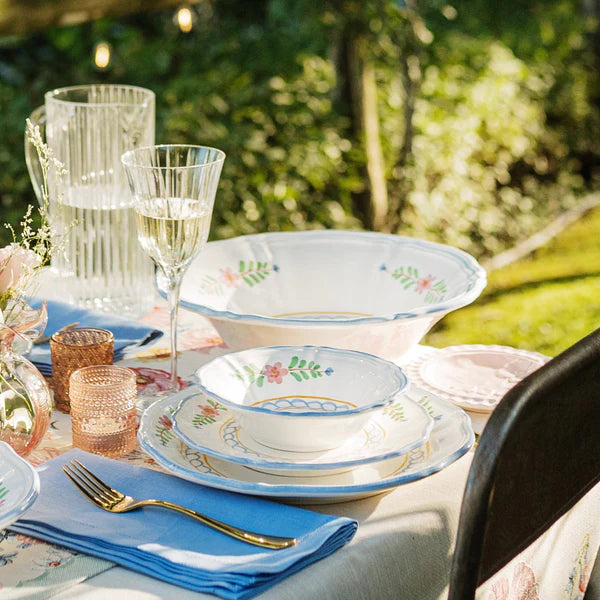 Outdoor table setting with floral-patterned dishes and glasses.