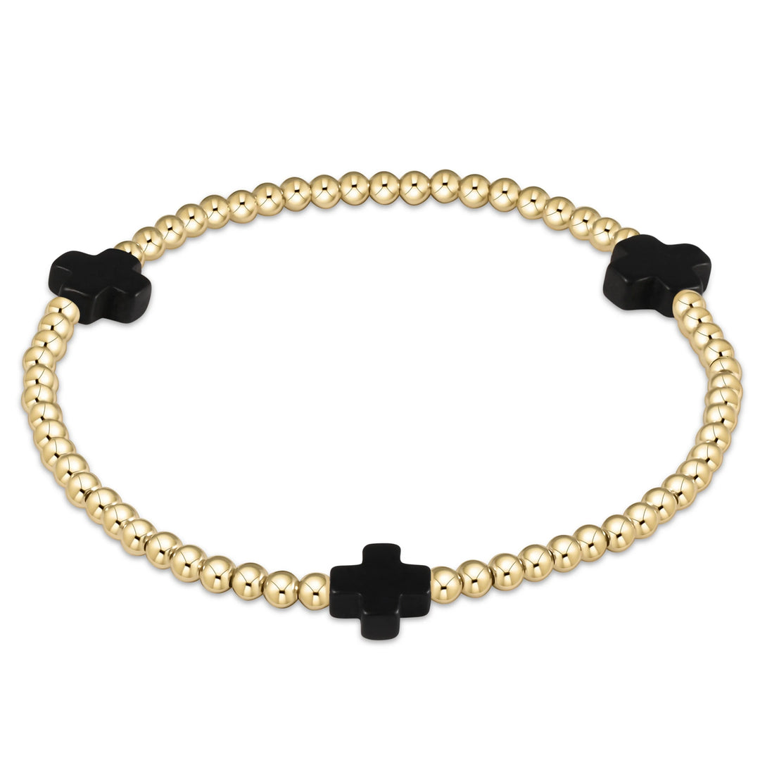 Gold beaded bracelet with black clover-shaped beads on a white background