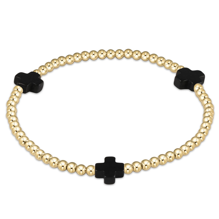 Gold beaded bracelet with black clover-shaped beads on a white background