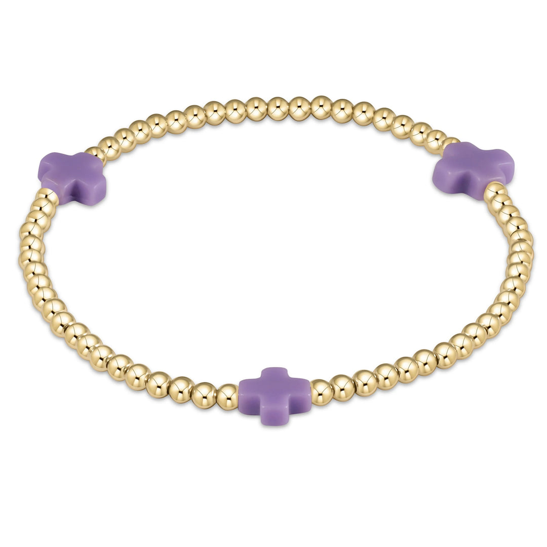 Gold bracelet with purple crosses on a white background