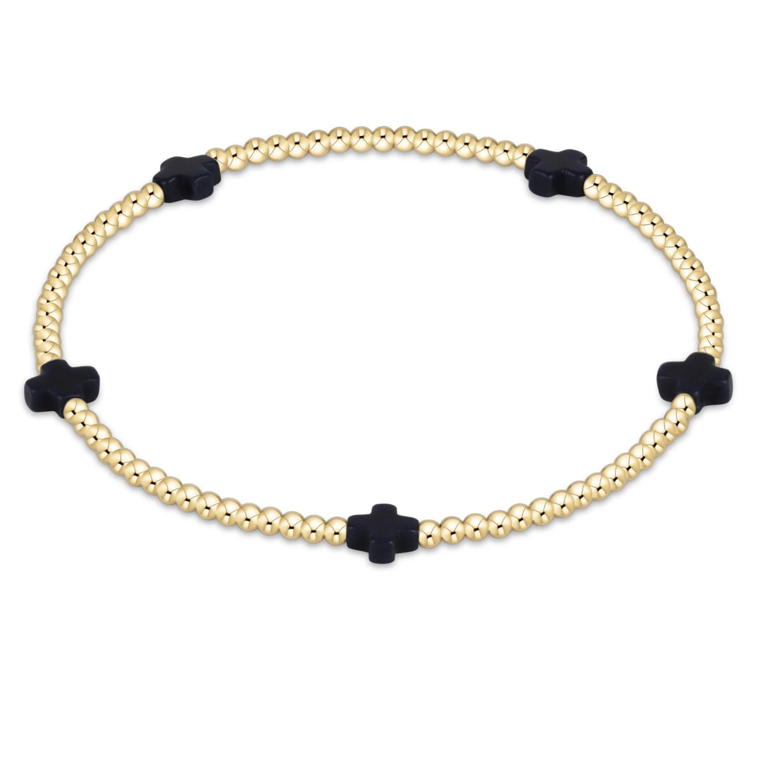 Bracelet with gold beads and navy cross-shaped ends on a white background