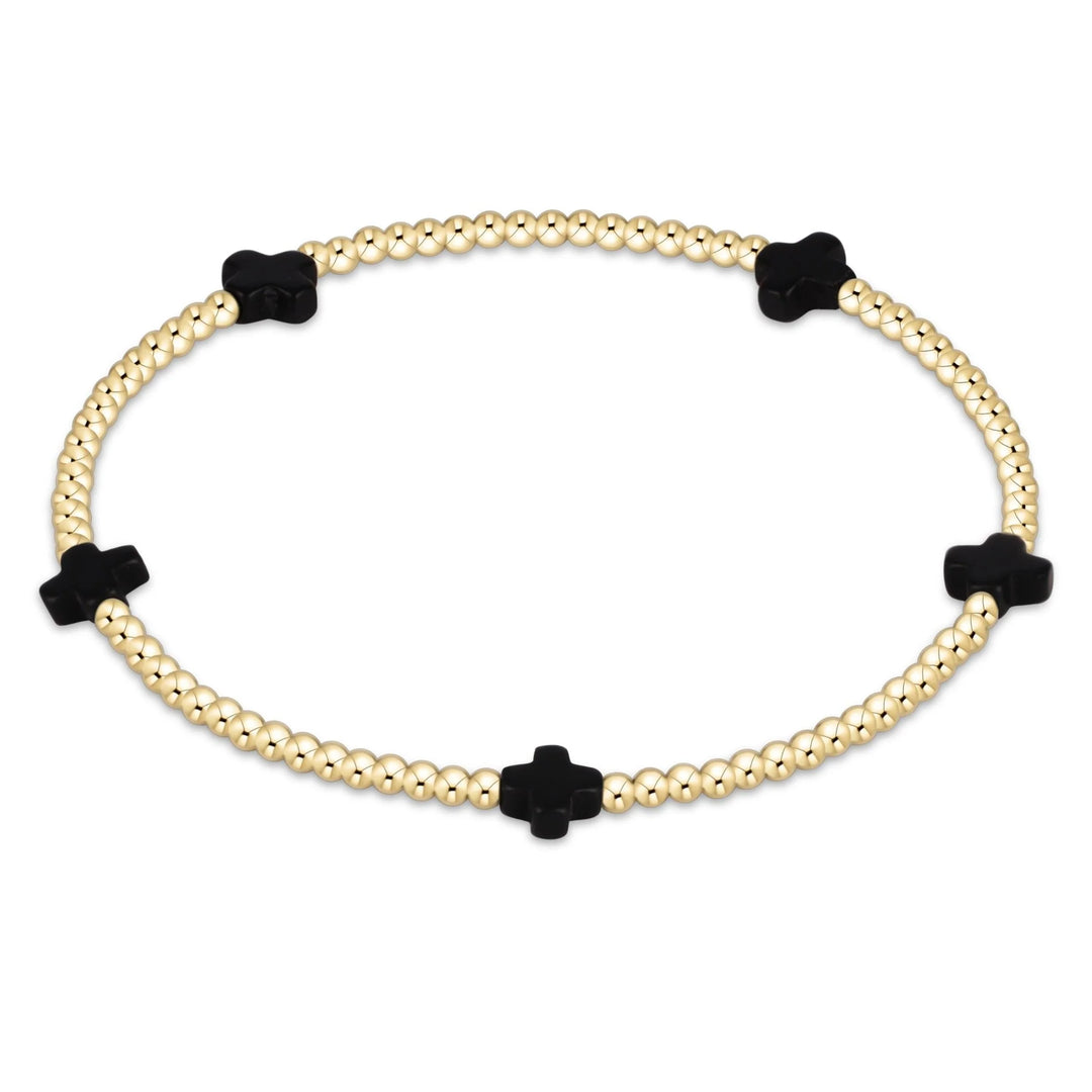 Bracelet with gold beads and black clover-shaped charms on a white background