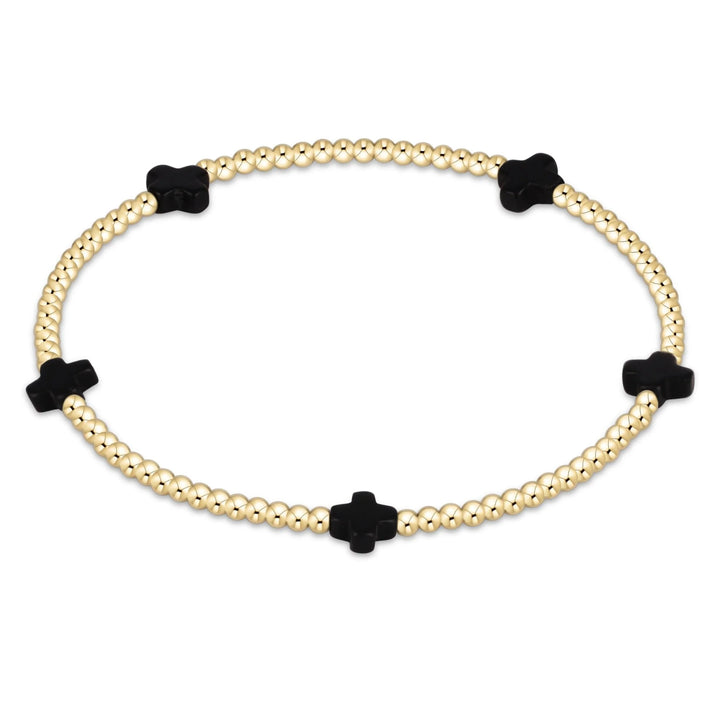 Bracelet with gold beads and black clover-shaped charms on a white background