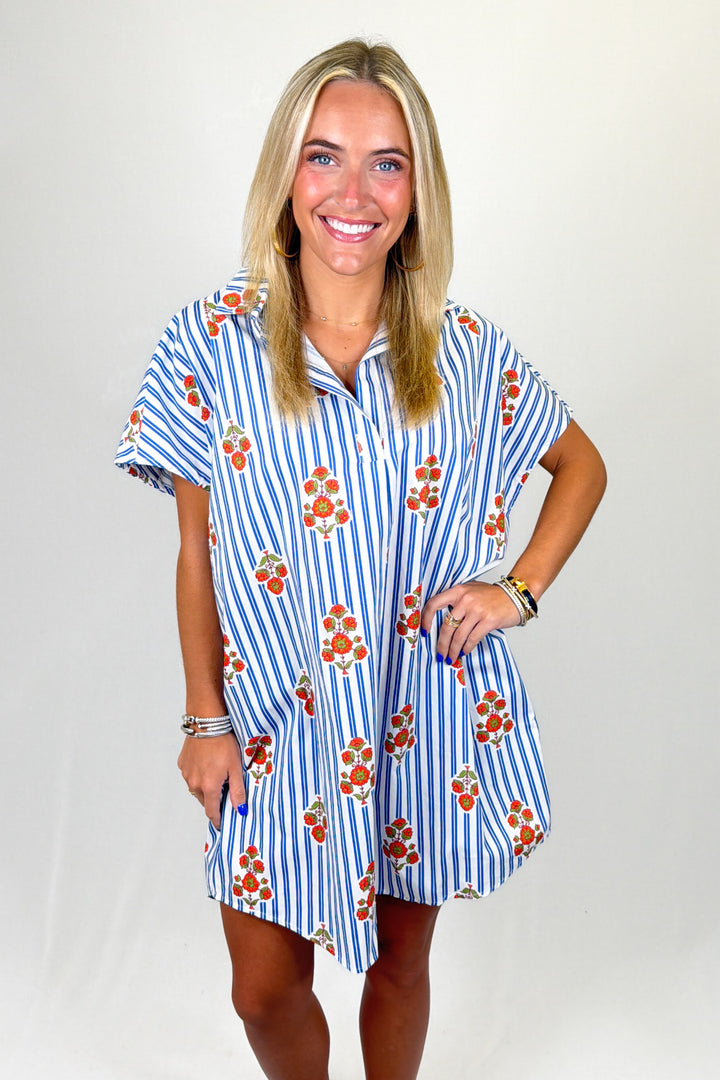 Woman wearing a blue and white striped dress with floral pattern on a plain background