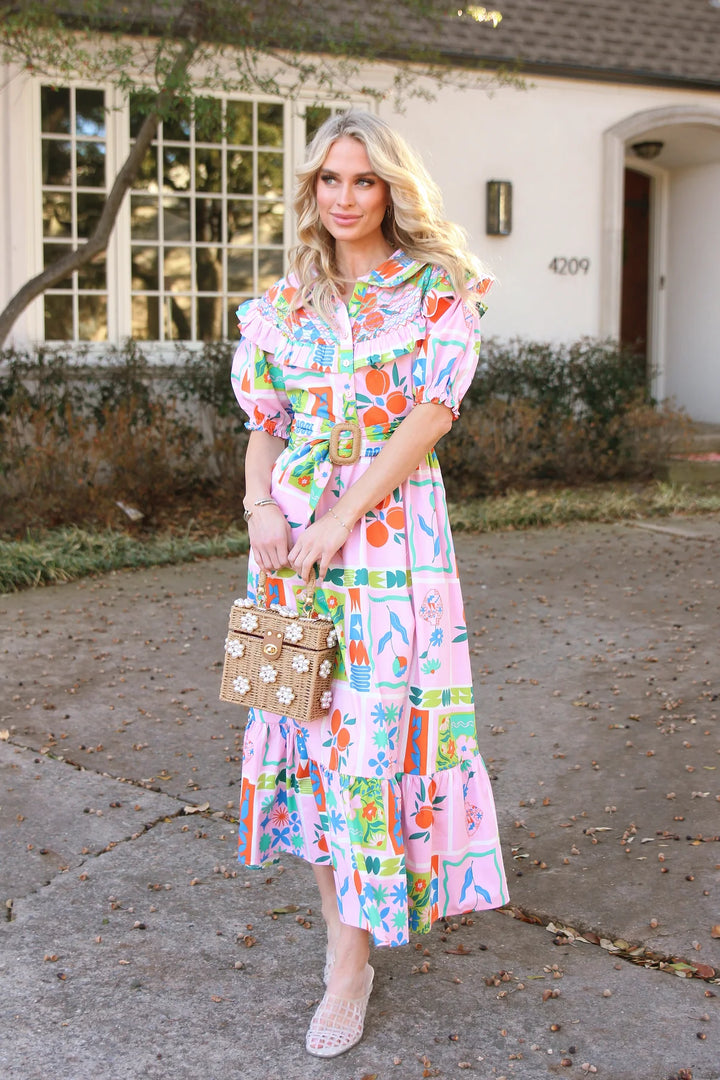 Woman in a colorful dress standing on a driveway with a house in the background