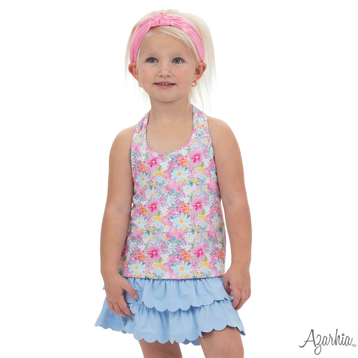 Young girl wearing a floral top and light blue skirt with a pink headband on a white background.